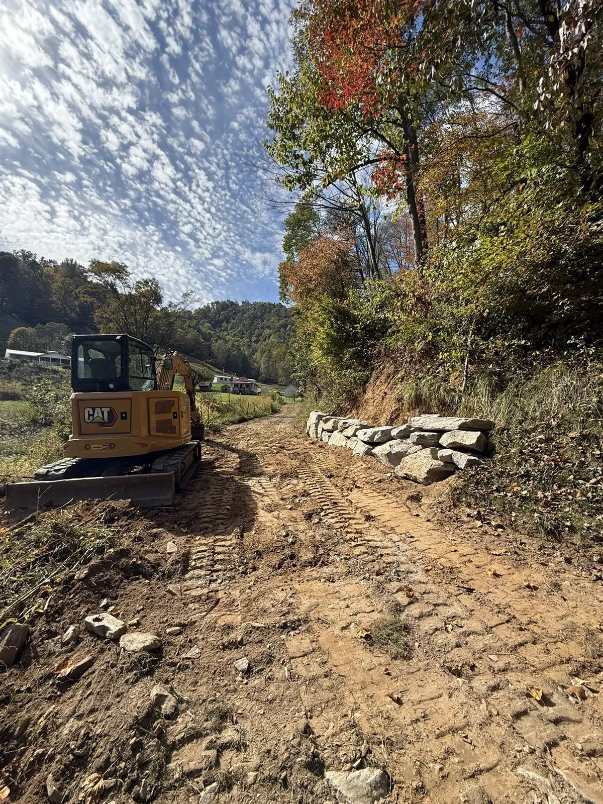 Excavator cutting a road grade into a rocky hillside near Spruce Pine, NC