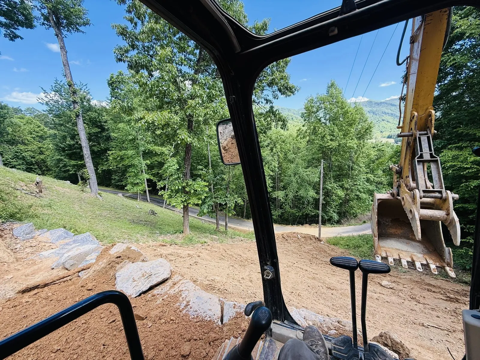 View from the excavator cab placing boulders along a graded mountain drive