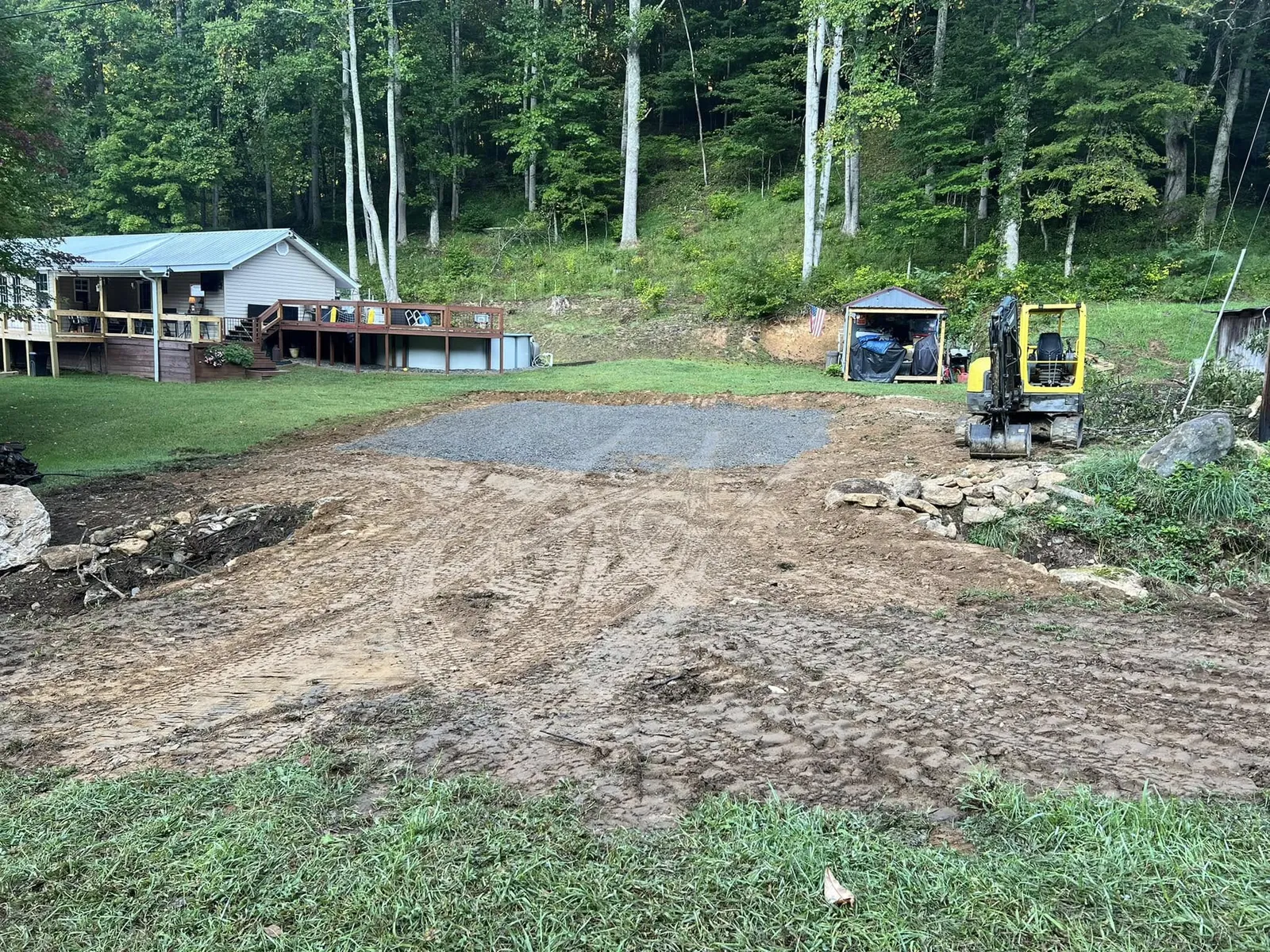 Compact excavator beside a freshly graded gravel building pad in Burnsville, NC