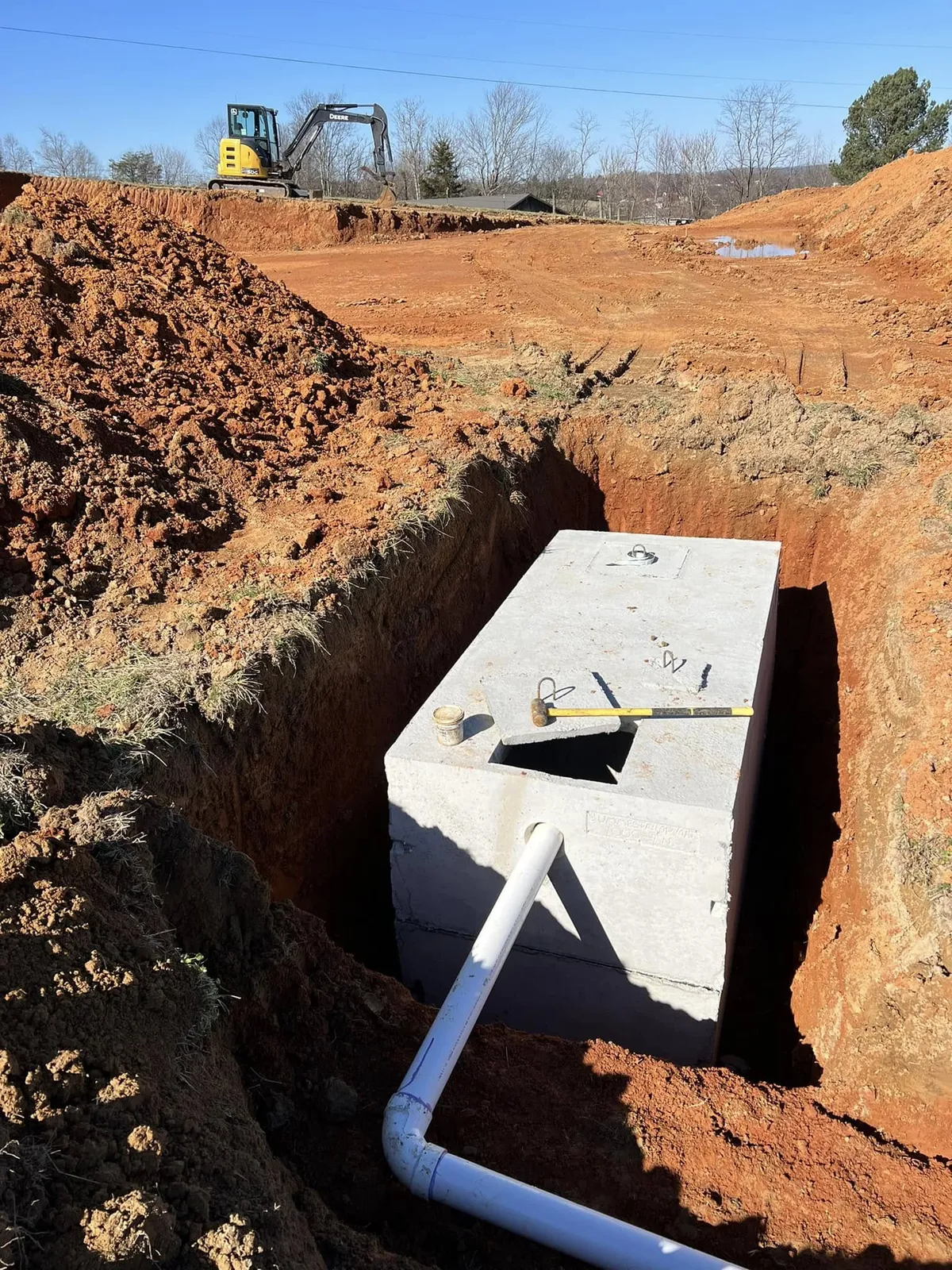 Concrete septic tank set in an excavation with PVC plumbing