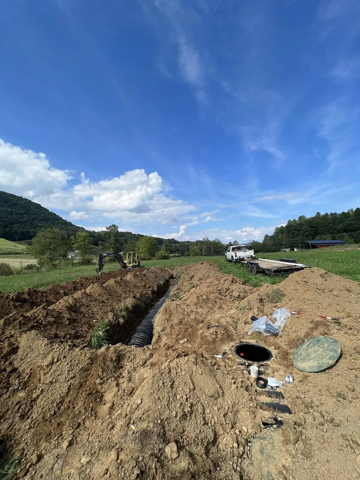 Drainage line trenched across a field with septic riser set, Western NC