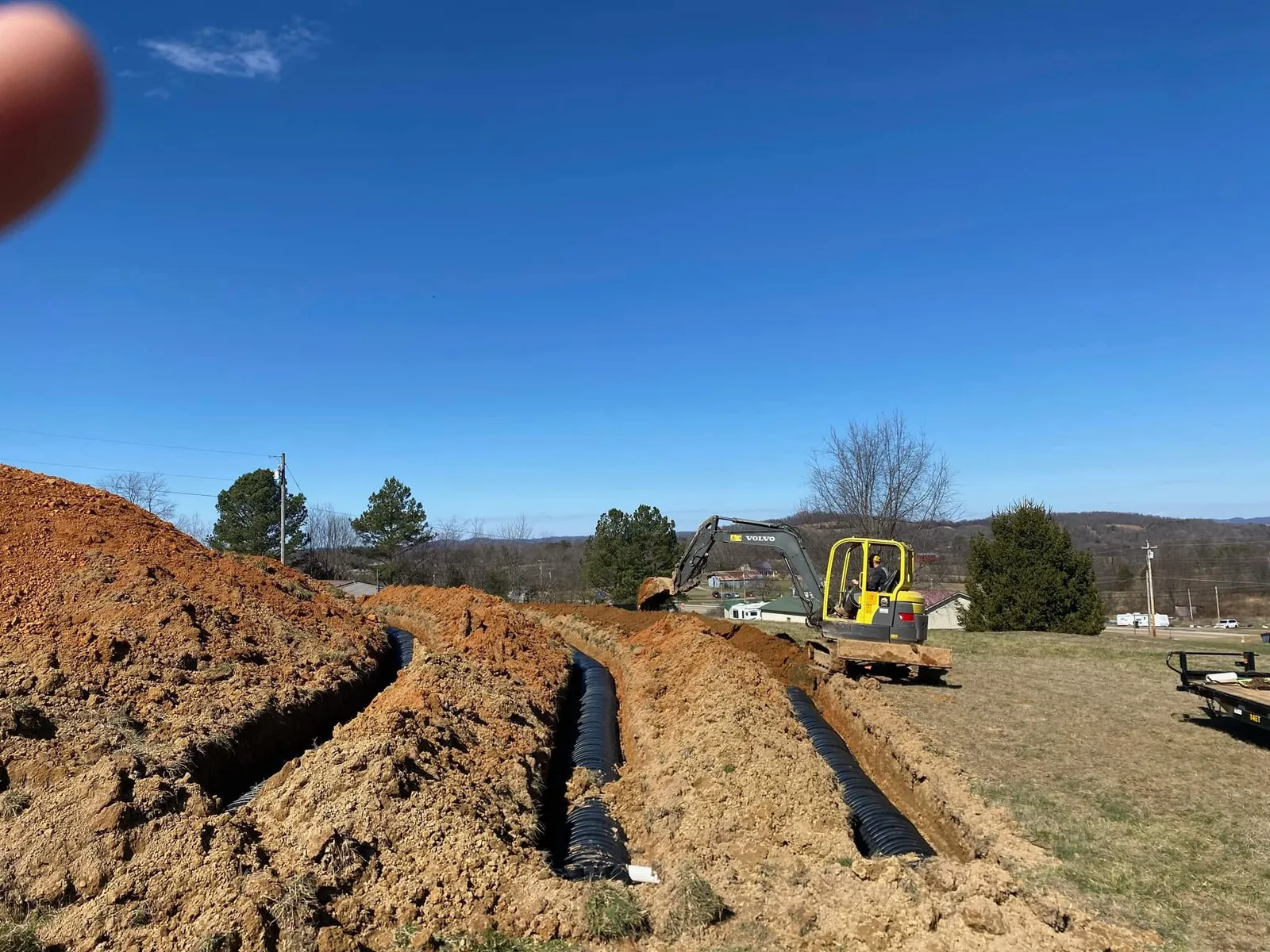 Multiple trenched drain-field laterals with excavator on site