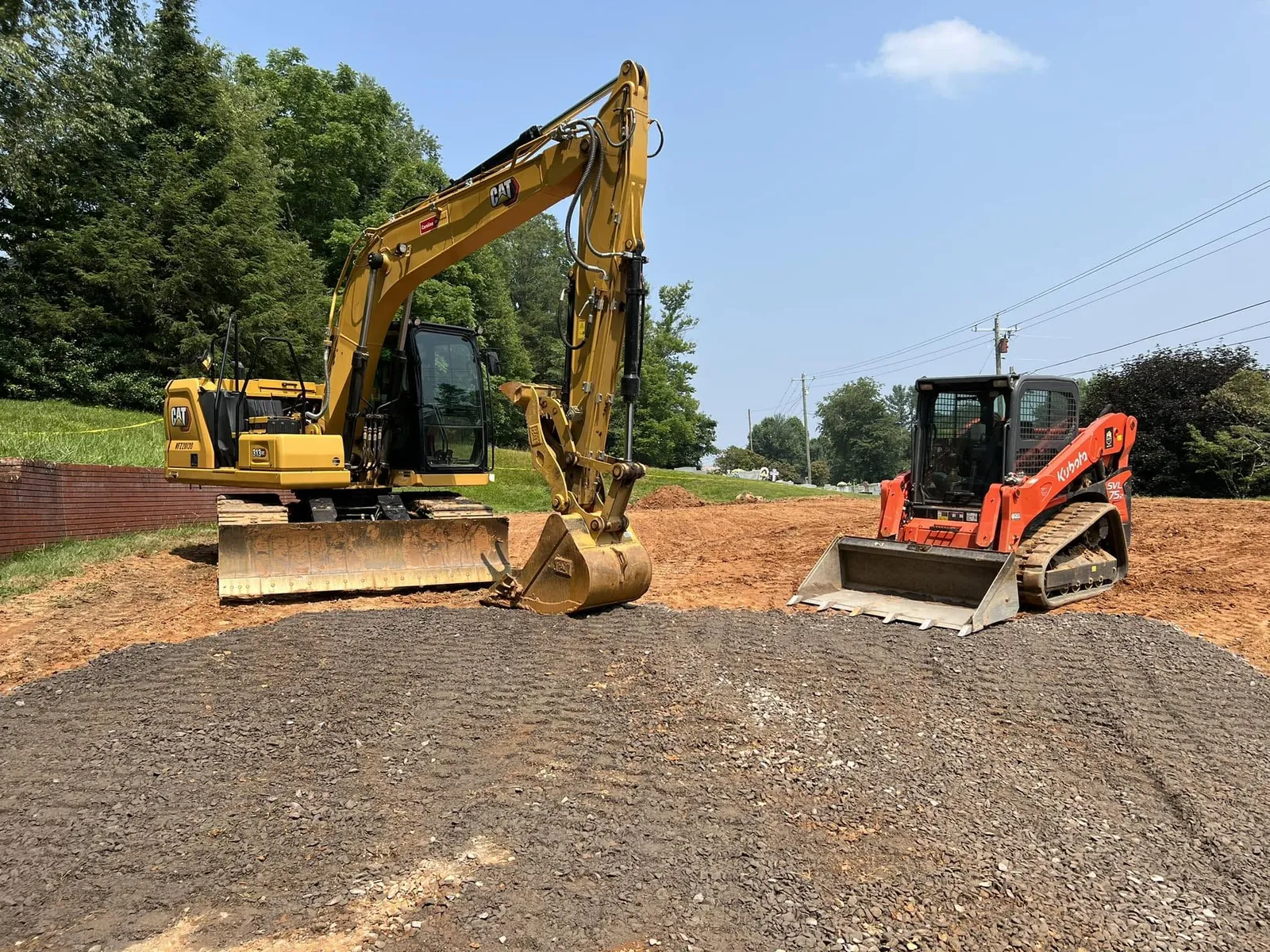 Excavator and skid steer staged on a graded high-elevation pad in Avery County, NC